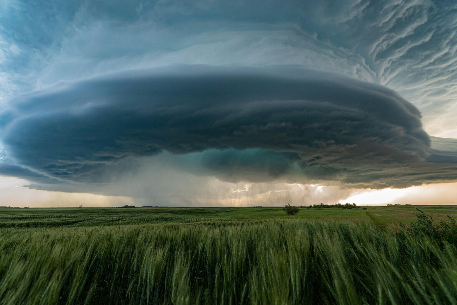 Grant Writing A powerful supercell storm looms over lush green fields in Saskatchewan, Canada.